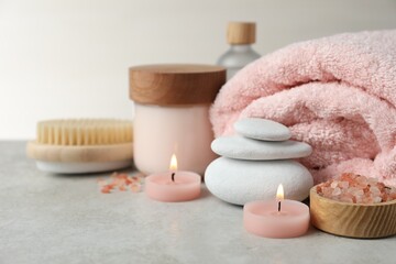 Beautiful composition with burning candles and different spa products on light grey table