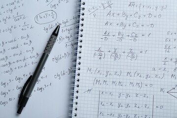 Paper with different mathematical formulas and pen, top view