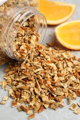 Jar with dried orange zest seasoning and fresh fruit on light grey table, closeup