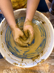 Serious young boy student of pottery class is molding clay on spinning potter's wheel, learning traditional craft. Serious child is concentrated on work, getting new experience.