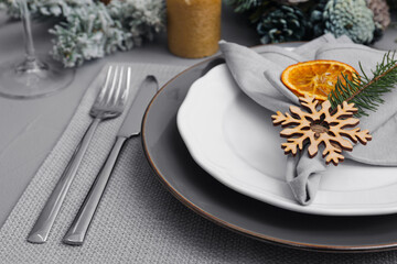 Festive place setting with beautiful dishware, fabric napkin and dried orange slice for Christmas dinner on grey table, closeup
