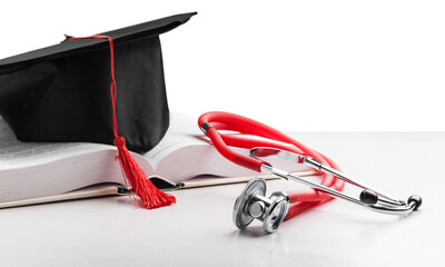 Medical stethoscope and graduate hat on the book.