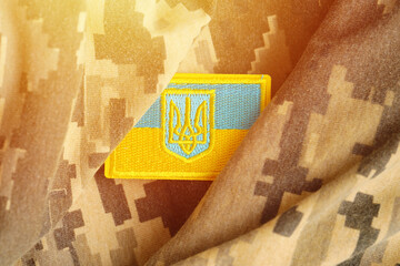Pixeled digital military camouflage fabric with ukrainian flag and coat of arms on chevron in blue...