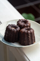 Caneles de bordeaux - traditional French sweet dessert. Canele on round white plate