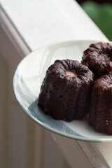 Caneles de bordeaux - traditional French sweet dessert. Canele on round white plate