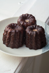 Caneles de bordeaux - traditional French sweet dessert. Canele on round white plate