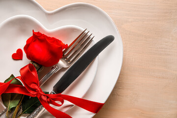 Fototapeta na wymiar Table setting for Valentine's Day with red rose and bow on wooden background, closeup