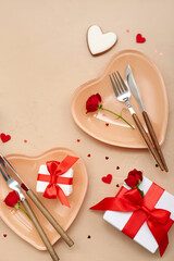 Table setting for Valentine's Day with gifts, roses and hearts on beige background