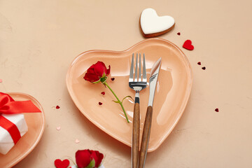 Table setting for Valentine's Day with roses and hearts on beige background