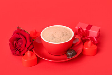 Cup of latte, rose, candy, candles and gift on red background. Valentine's Day celebration