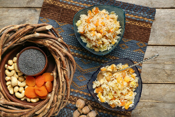 Bowls of rice Kutya, ingredients and wreath on wooden background
