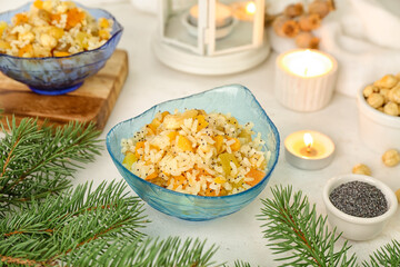 Bowl of rice Kutya and Christmas branches on white table, closeup