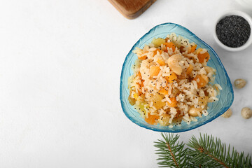 Bowl of rice Kutya and Christmas branches on white table, closeup