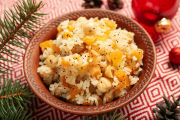Bowl of rice Kutya and Christmas branches on napkin, closeup