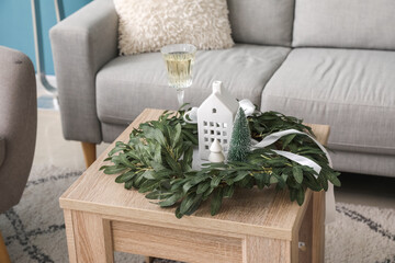 Christmas wreath, candle holder and glass of champagne on table in living room, closeup
