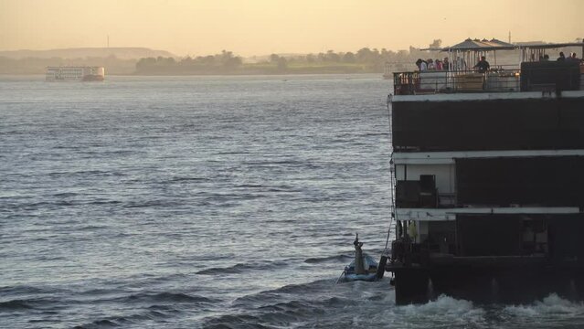 Man selling merchandise from a boat to a ship in the Nile River, Egypt