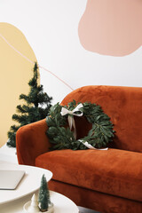 Red sofa with Christmas wreath and fir tree in living room