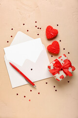 Blank letter with gift, candles and hearts on beige background. Valentine's Day celebration