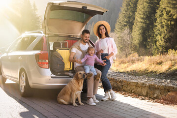 Parents, their daughter and dog near car outdoors. Family traveling with pet