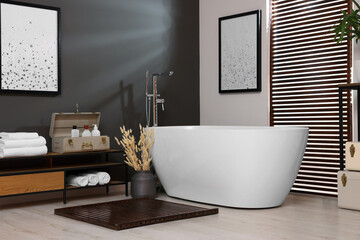 Fototapeta na wymiar Stylish bathroom interior with ceramic tub, towels and cosmetic products