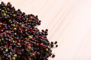 Tasty elderberries (Sambucus) on wooden table, top view. Space for text