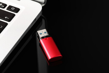 Modern usb flash drive near laptop on black table
