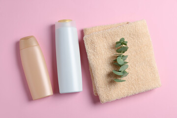 Obraz na płótnie Canvas Soft folded towel with eucalyptus branch and cosmetic products on pink background, flat lay
