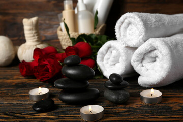 Fototapeta na wymiar Beautiful spa composition for Valentine's Day with stones, candles, towels and rose flowers on wooden background
