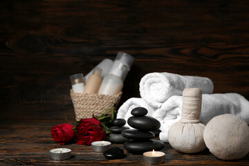 Beautiful spa composition for Valentine's Day with stones, candles, towels, herbal bags and rose flowers on wooden background
