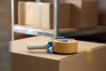 Adhesive tape dispenser on cardboard box indoors