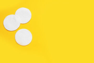 Soft clean cotton pads on yellow background, flat lay. Space for text