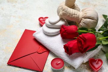 Beautiful spa composition for Valentine's Day with rose flowers, towel, envelope, herbal bags, candles and stones on light background