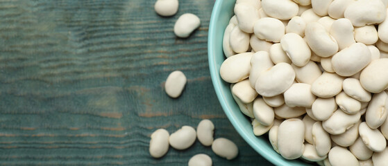 Bowl of white beans and space for text on blue wooden table, top view. Banner design