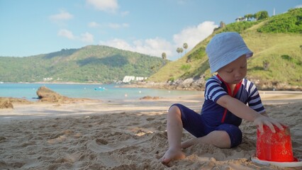 A little boy in a swimming suit carelessly spends time playing on the shores of a tropical sea.