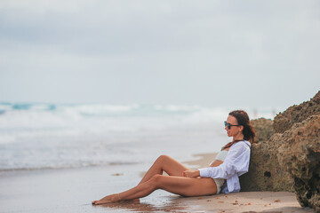 Young happy woman on the beach enjoy her summer vacation. Girl is happy and calm in her stay on the beach