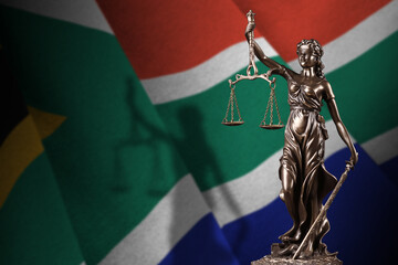 South Africa flag with statue of lady justice and judicial scales in dark room. Concept of...