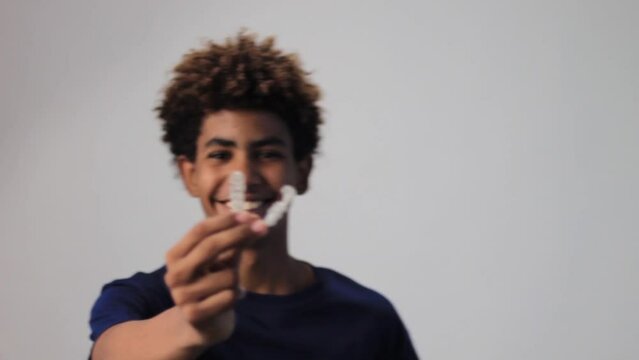 video of a handsome teenager afro latin smiling holding a dentals aligner
