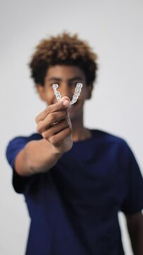video of a handsome teenager afro latin smiling holding a dentals aligner