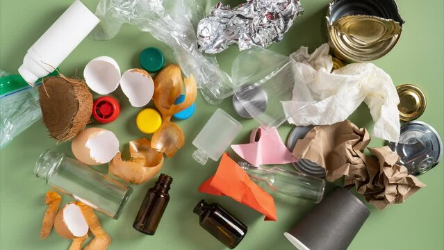 Animation of garbage, rubbish of plastic, metal, organic, glass and food, plastic bottles and bags appearing on green background. Ecological safety, zero waste and responsibility. Stop motion video