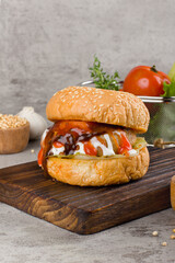 Home made hamburger with beef, onion, tomato, lettuce and cheese. Fresh burger closeup on wooden rustic table with potato fries and chips.