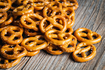 Salty mini party pretzels on a wooden surface close-up.