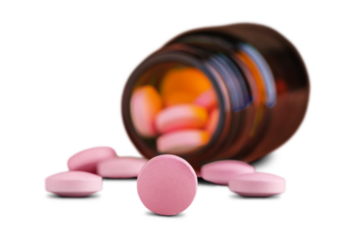 Round medical pill scattered in front of the bottle