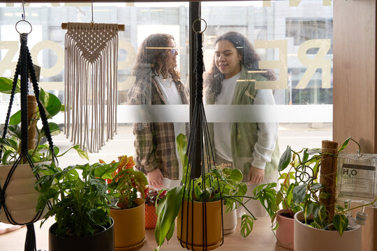 Young Couple Looking In Window Of House Plant Shop