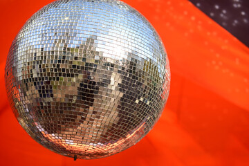 Shiny disco ball or mirrorball on a bright orange background, outdoor party with mirror disco ball