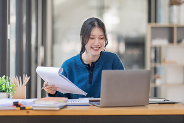 Business Asian woman Using laptop computer and working at office with calculator document on desk, doing planning analyzing the financial report, business plan investment, finance analysis concept.