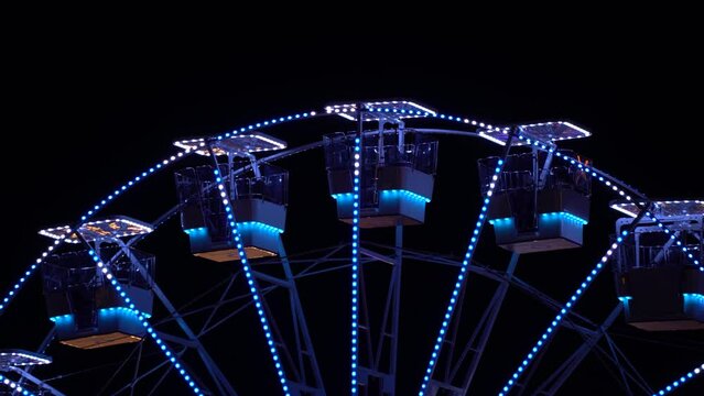 Ferries wheel illuminated by colorful neon lights in night black background, playground concept