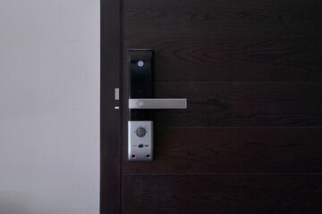 Digital door lock on black wooden door panel., door with a keyhole