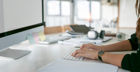 Cropped shot of young woman hand working on desktop computer in modern office room.