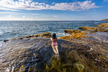 GIRL IS RELAXING AND SWIMMING IN THE WATER OF THE HANG RAI SEA IN NINH THUAN, VIETNAM - obrazy, fototapety, plakaty