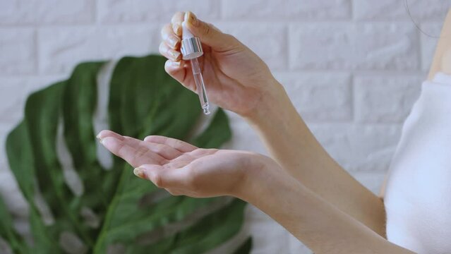 Asian woman applying by dropping essential oil on hand for spa ans skin care. 4K video beauty and spa treatment concept.
